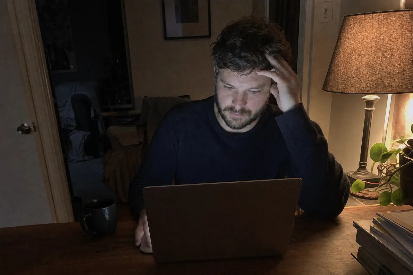 A freelancer at his desk late at night, stuck rewriting a payment reminder email