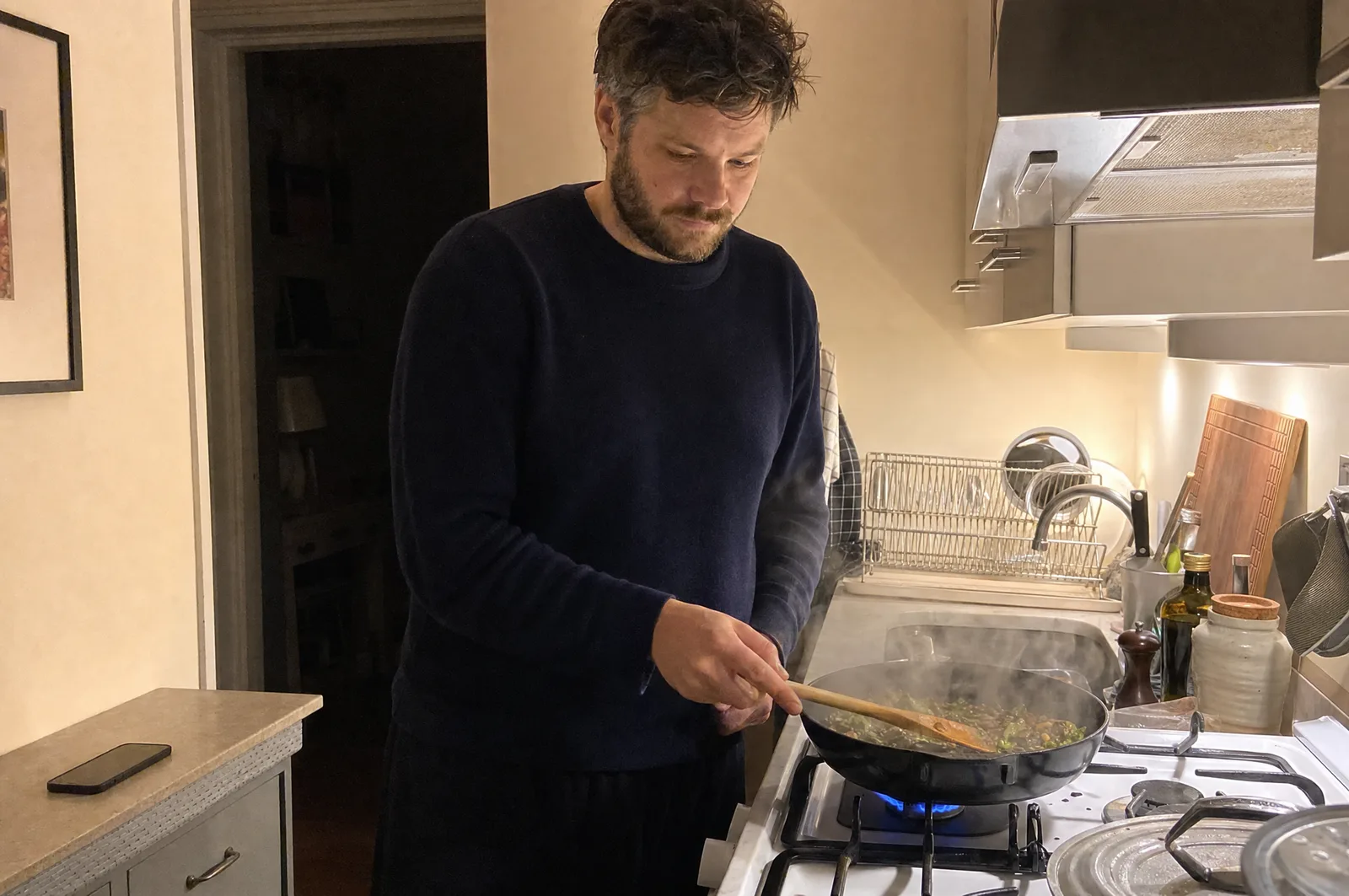 A freelancer cooking dinner in the evening, phone face-down on the counter